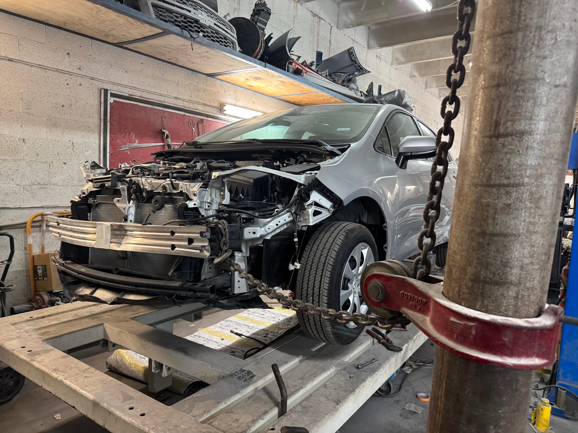 Silver Toyota Corolla on the frame rack with the front end stripped for structural repair