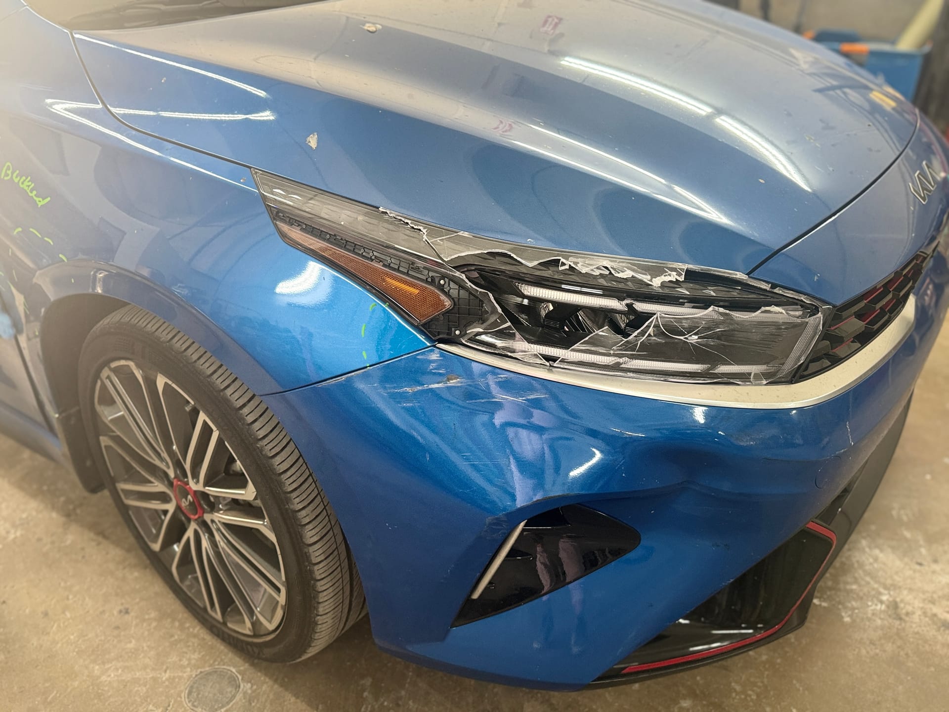 Kia Forte GT with a cracked front bumper and broken headlight before repair