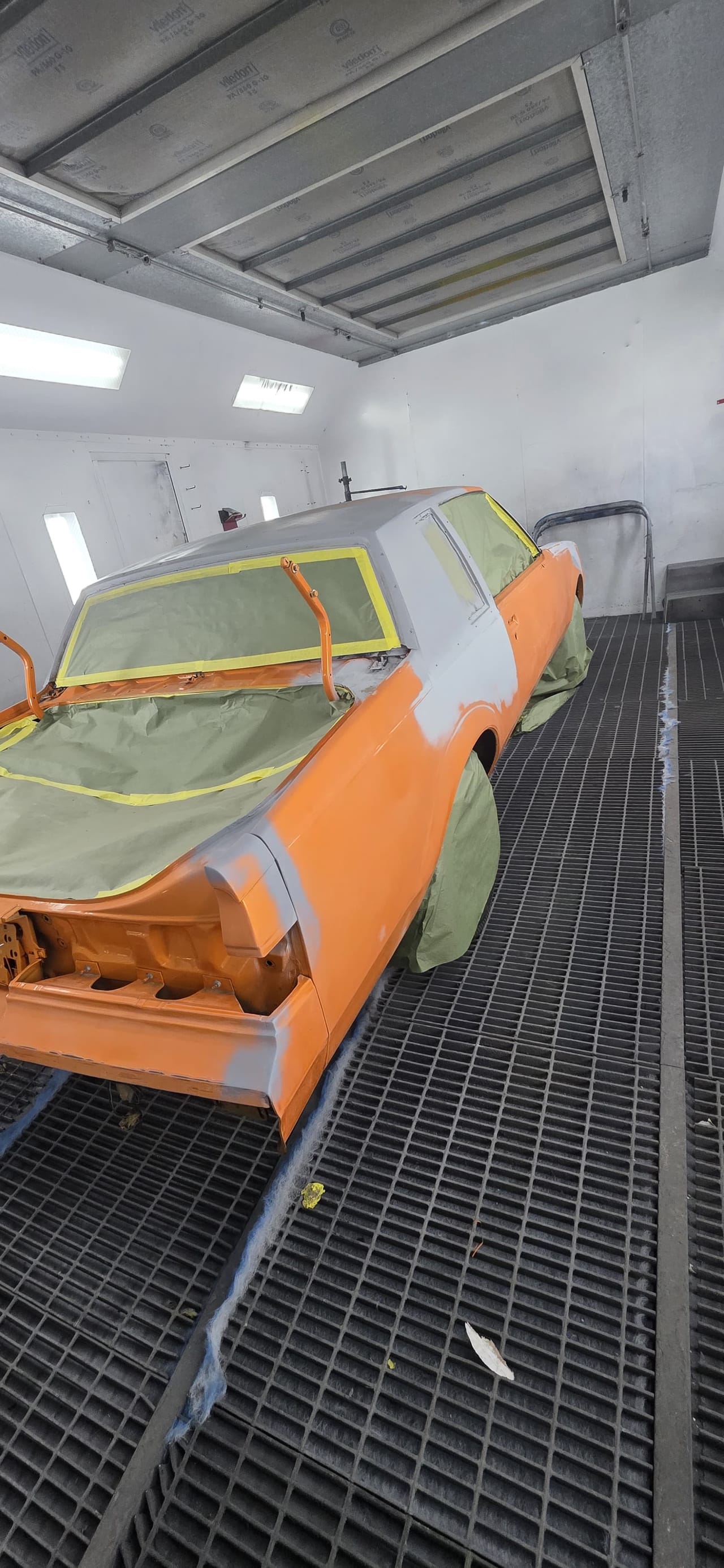 The same Malibu masked with tape and paper in the booth, hood off, ready for paint