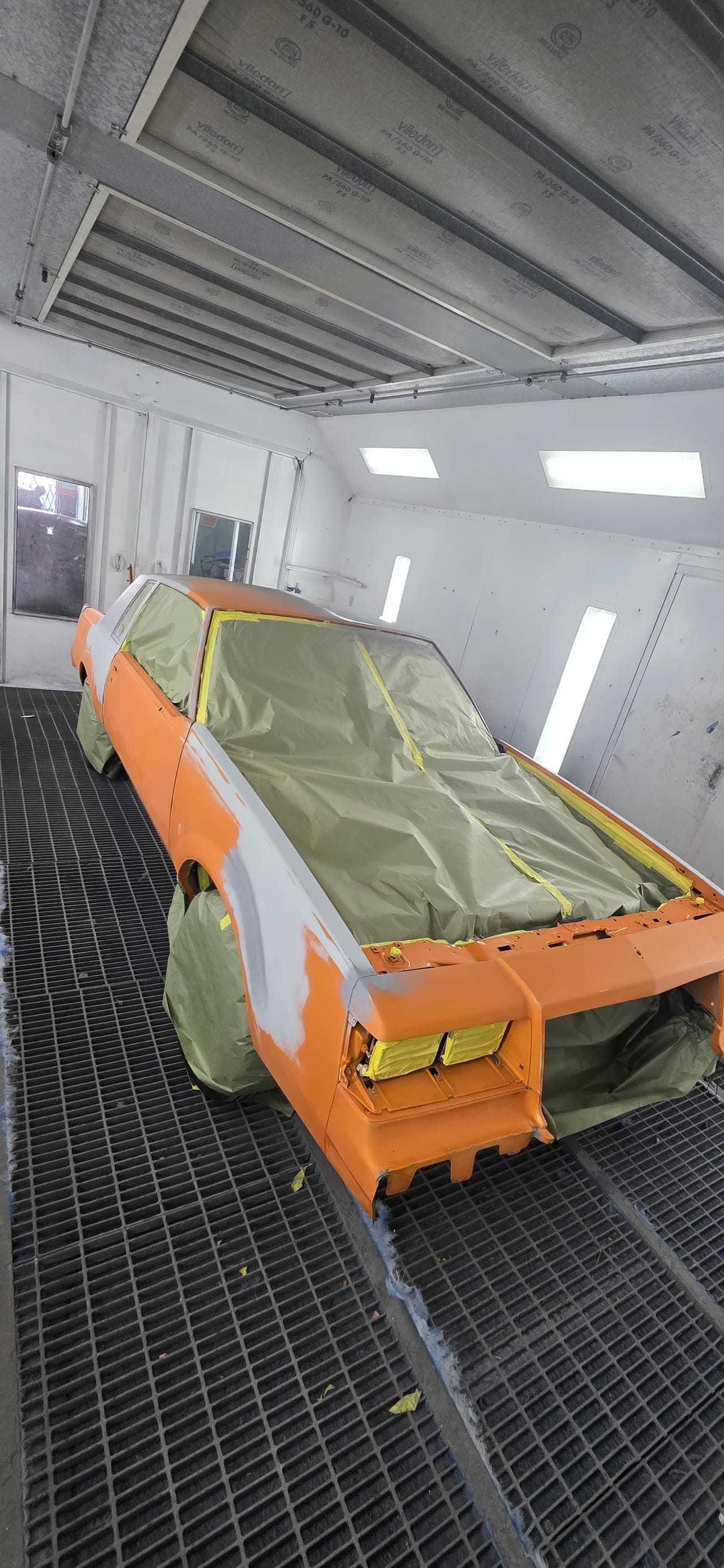 Classic Chevy Malibu in primer inside the KAG paint booth before paint, bare-metal spots marked