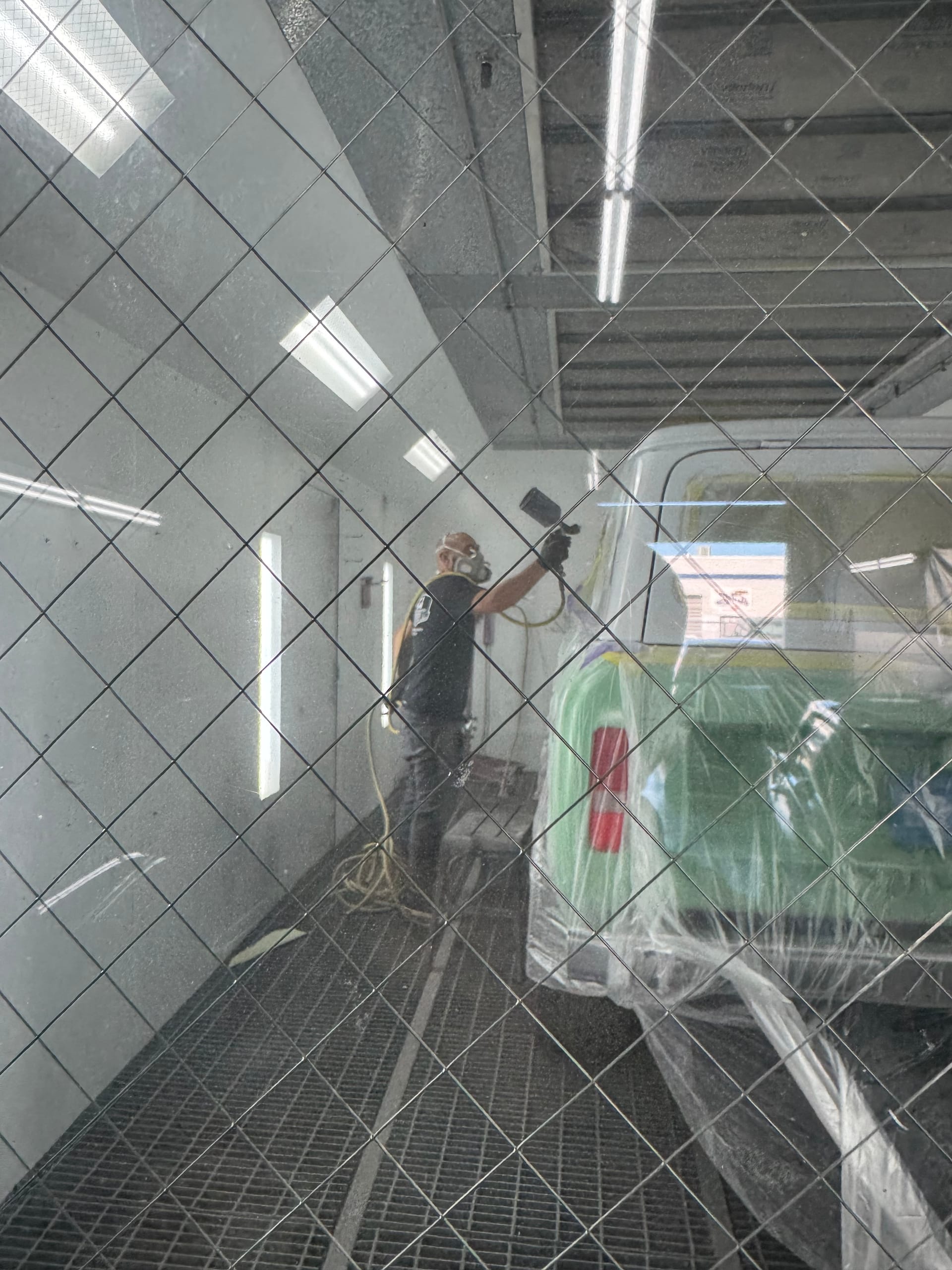 Technician spraying a green Ford Ranger inside the KAG paint booth