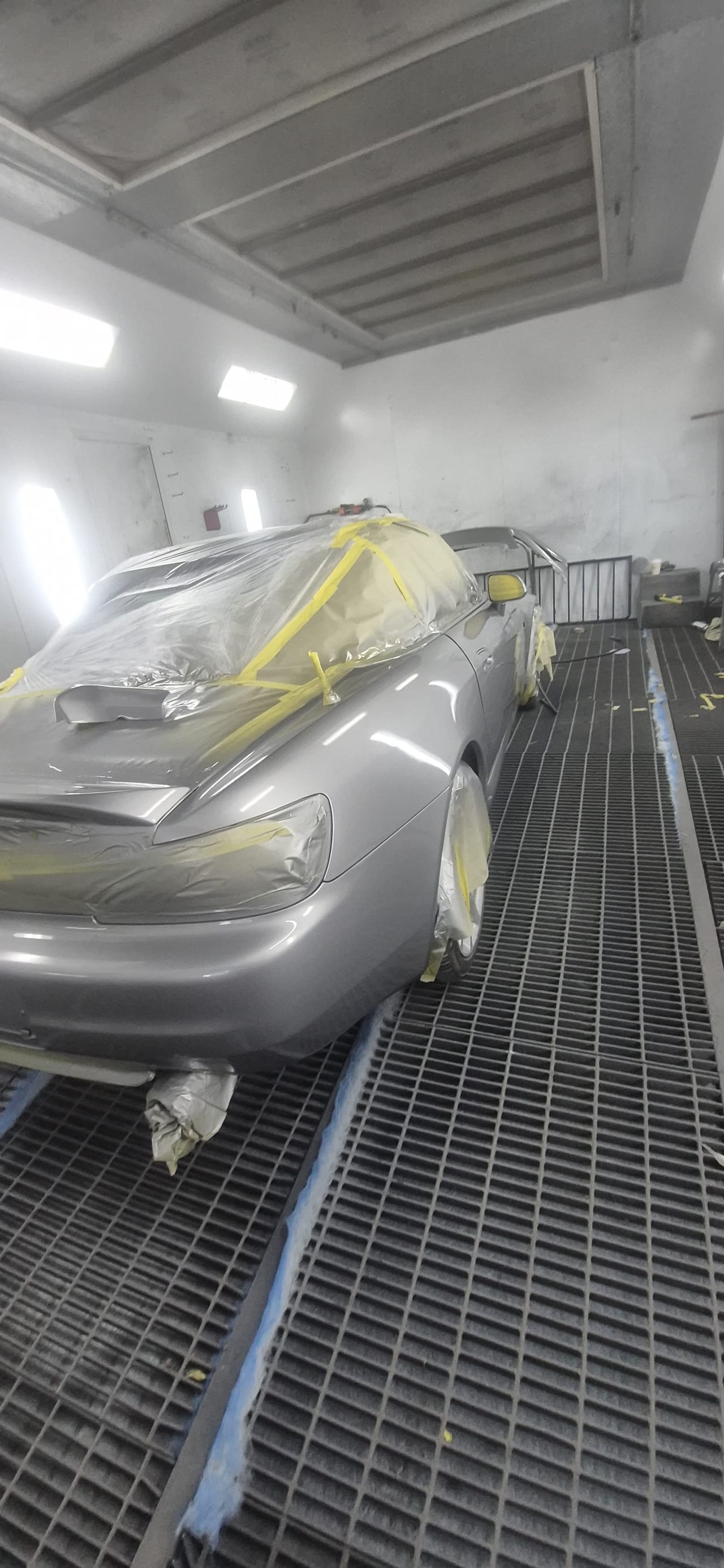 The roadster fully masked in the booth, front view, ready for paint at KAG